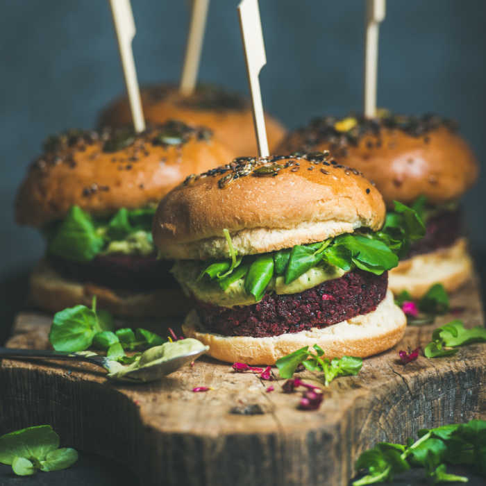 Healthy homemade vegan burger with beetroot-quinoa patty, arugula, avocado sauce