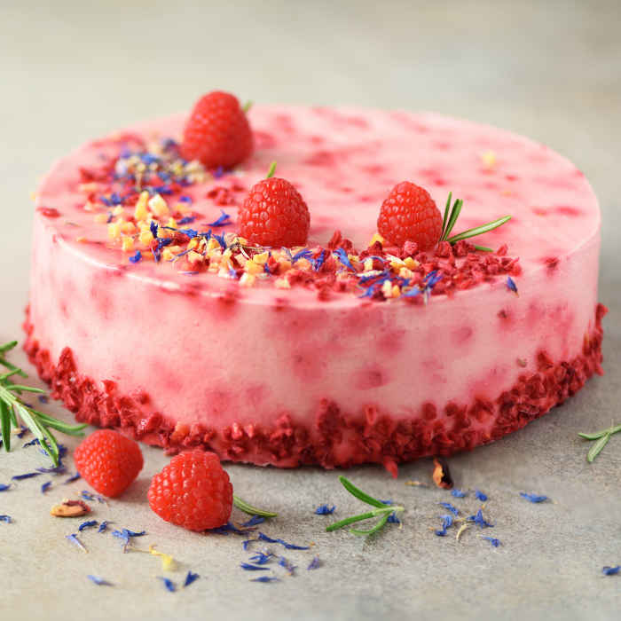 Delicious raspberry cake with fresh berries, rosemary and dry flowers on gray concrete background