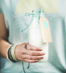 Young woman holding bottle of dairy-free almond milk