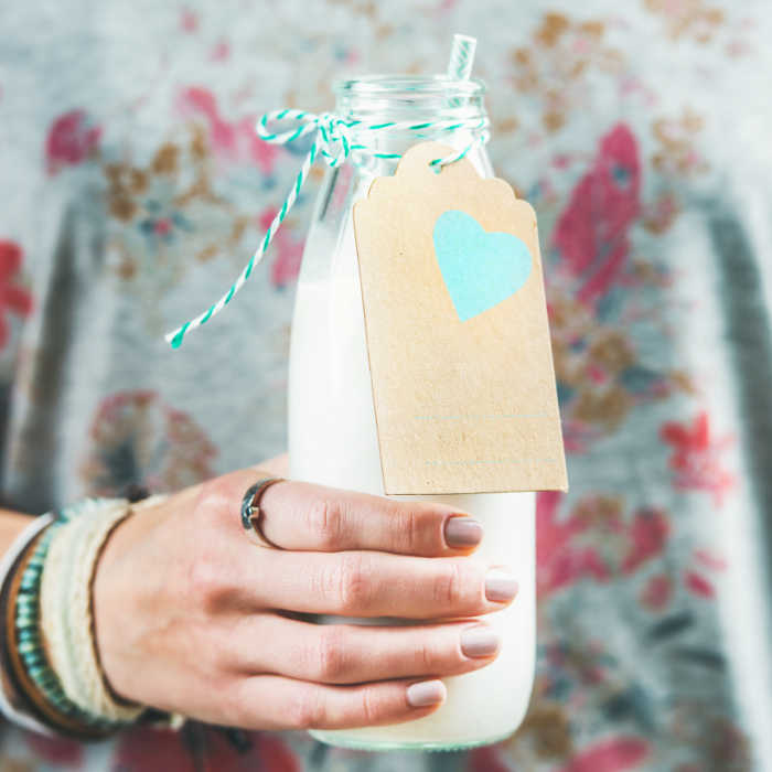 Young woman holding bottle of dairy-free almond milk in hand