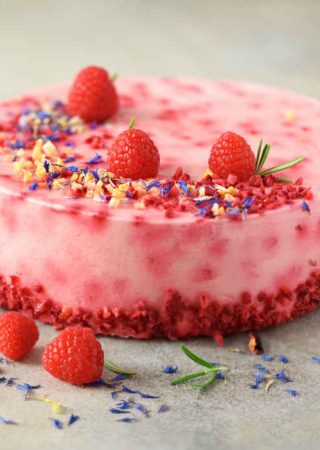 Delicious raspberry cake with fresh berries, rosemary and dry flowers on gray concrete background